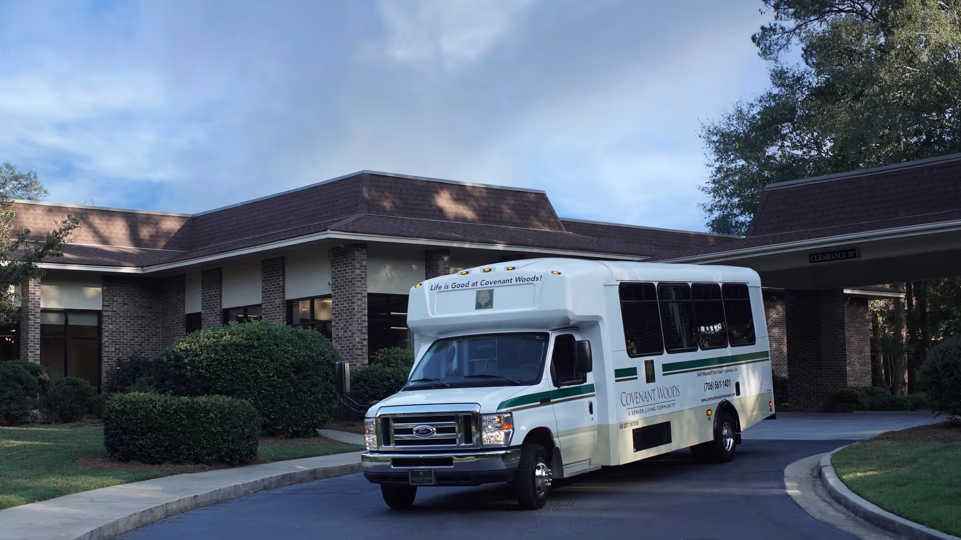 A shuttle bus arriving at the entrance of Covenant Woods senior living facility.