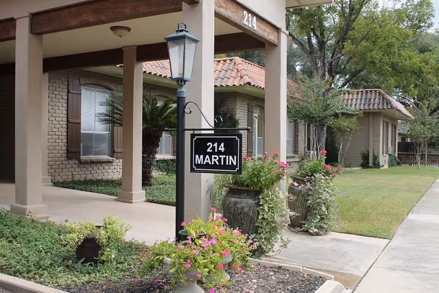 Front entrance of 214 Martin-A Retirement Residence with sign and landscaped planters.