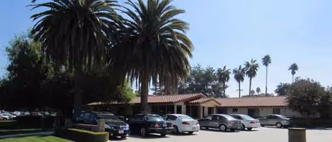 Exterior view of Valencia Gardens Health Care Center with cars and palm trees