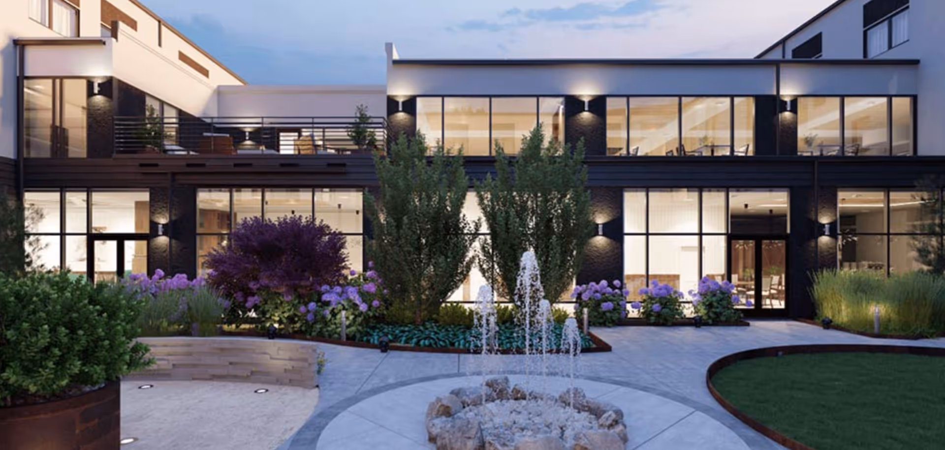 Modern multi-story building with large floor-to-ceiling windows overlooking a landscaped courtyard with a central water fountain.