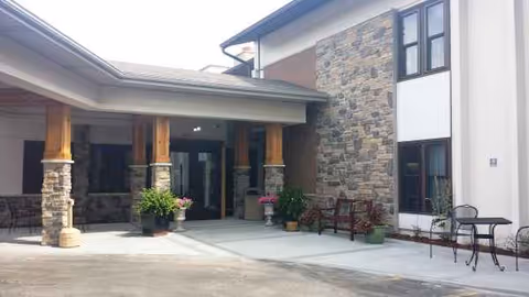 Entrance of Kensington Care and Rehab Center with stone exterior, columns, and outdoor seating.