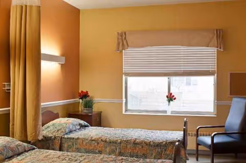 Two twin beds with patterned quilts, nightstands, and a window in a bright bedroom.