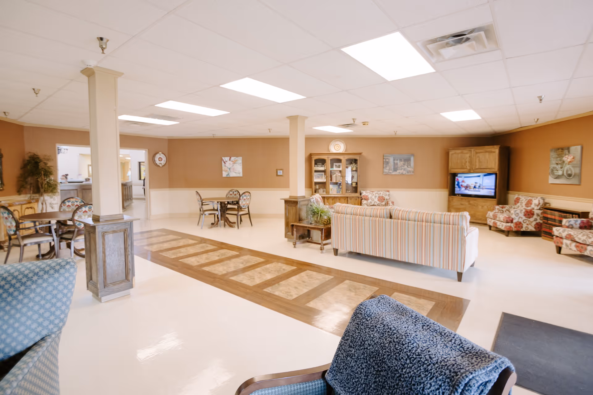 Spacious common area with sofas, armchairs, dining tables, and a TV cabinet.