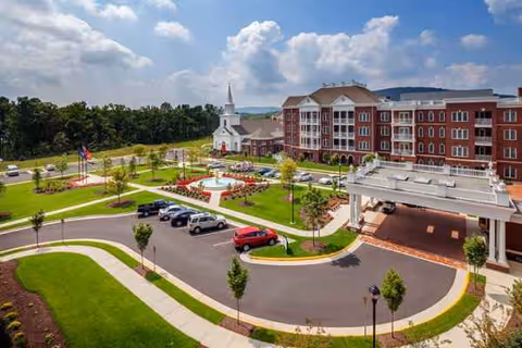 A brick senior living building with a circular drive, parking lot, and manicured lawns.