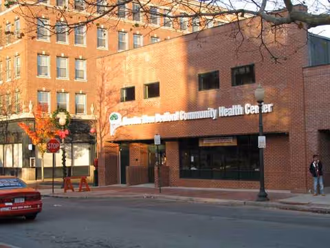 Brick-front health center on a city street with a stop sign.