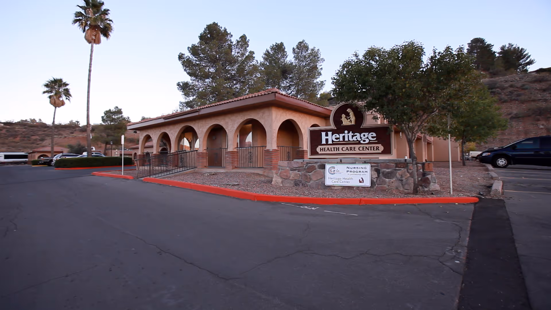 Exterior view of the Heritage Health Care Center with palm trees and a clear sky.