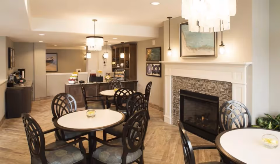 Cozy dining/common area with round tables and chairs, a fireplace, and a beverage station.
