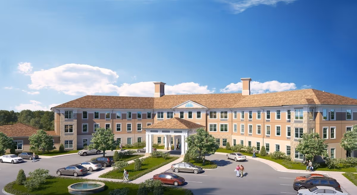 Exterior view of a large three-story senior living facility building with a covered entrance, surrounded by trees, parked cars, and people walking on the driveway and sidewalks under a clear blue sky.