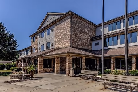 Front exterior of Elizabeth Gardens senior living facility with brick facade, entrance, and benches.
