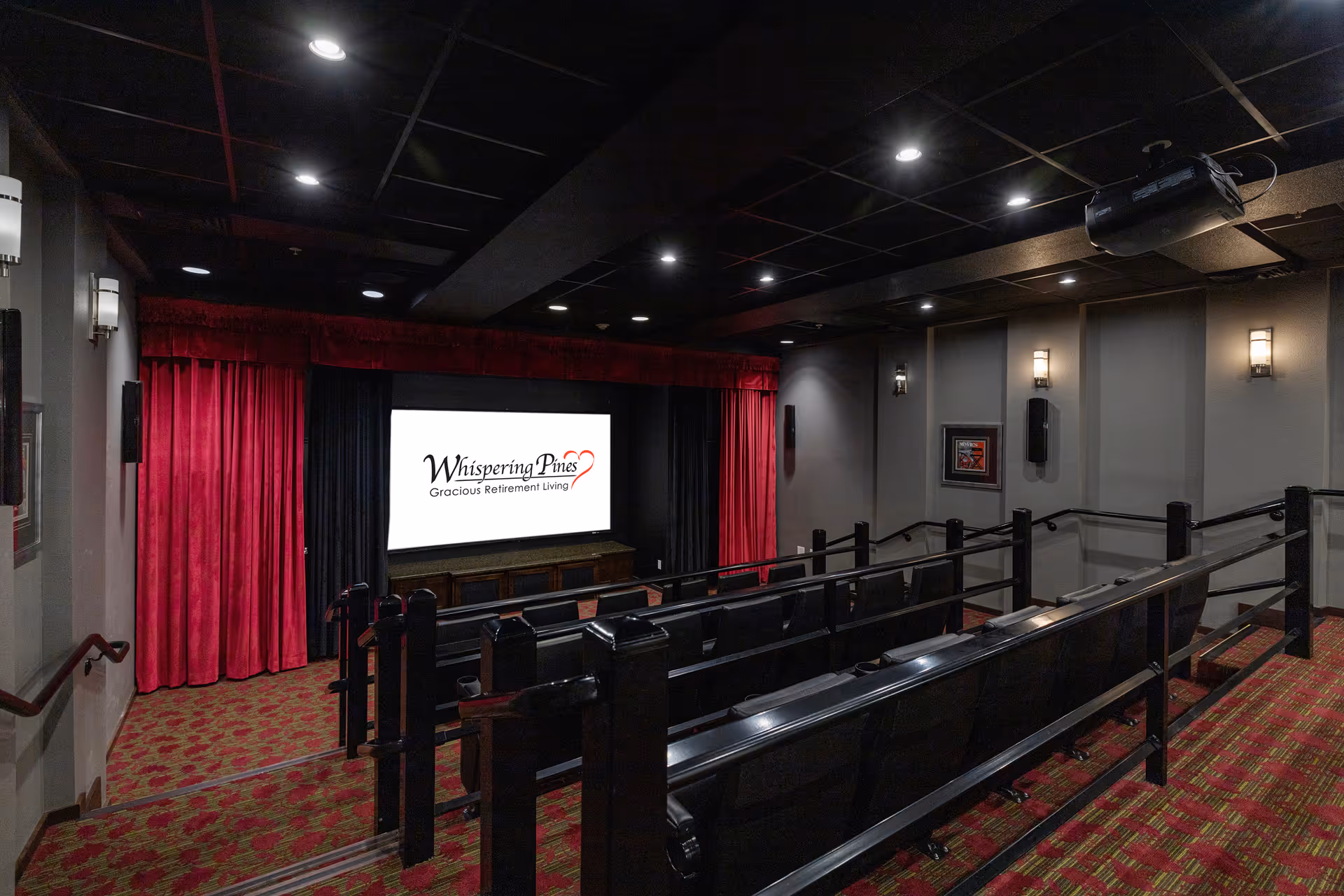 Small theater-style screening room with tiered seating, red curtains and carpet, and a screen displaying "Whispering Pines Gracious Retirement Living."