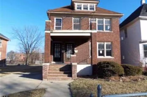 Brick two-story building with front steps and a small lawn.
