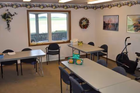 A senior living community dining room with tables, chairs, decorations, and a window view.