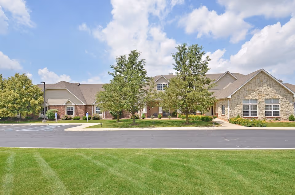 Front view of a senior living facility with brick and stone exterior and manicured lawn.