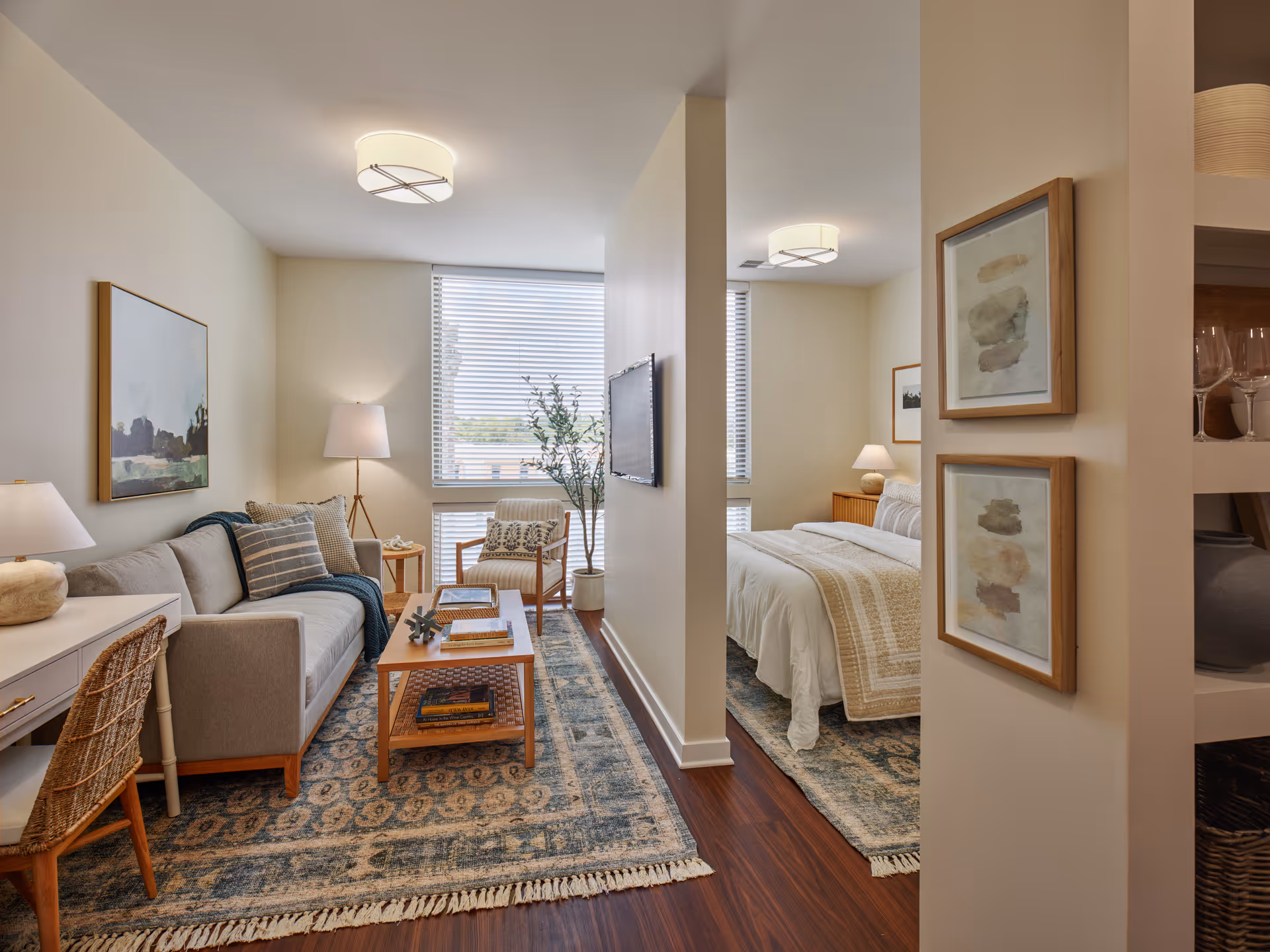 Open studio-style apartment interior with a living area, coffee table, and adjacent bedroom separated by a partial wall.