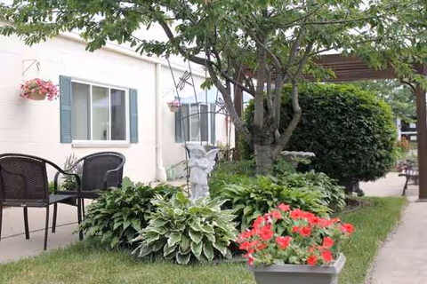 Outdoor patio area of a senior living facility with seating, planters, and greenery.