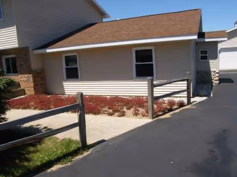 Exterior view of Culver Meadows Adult Foster Care building with beige siding, driveway, and mulched beds.