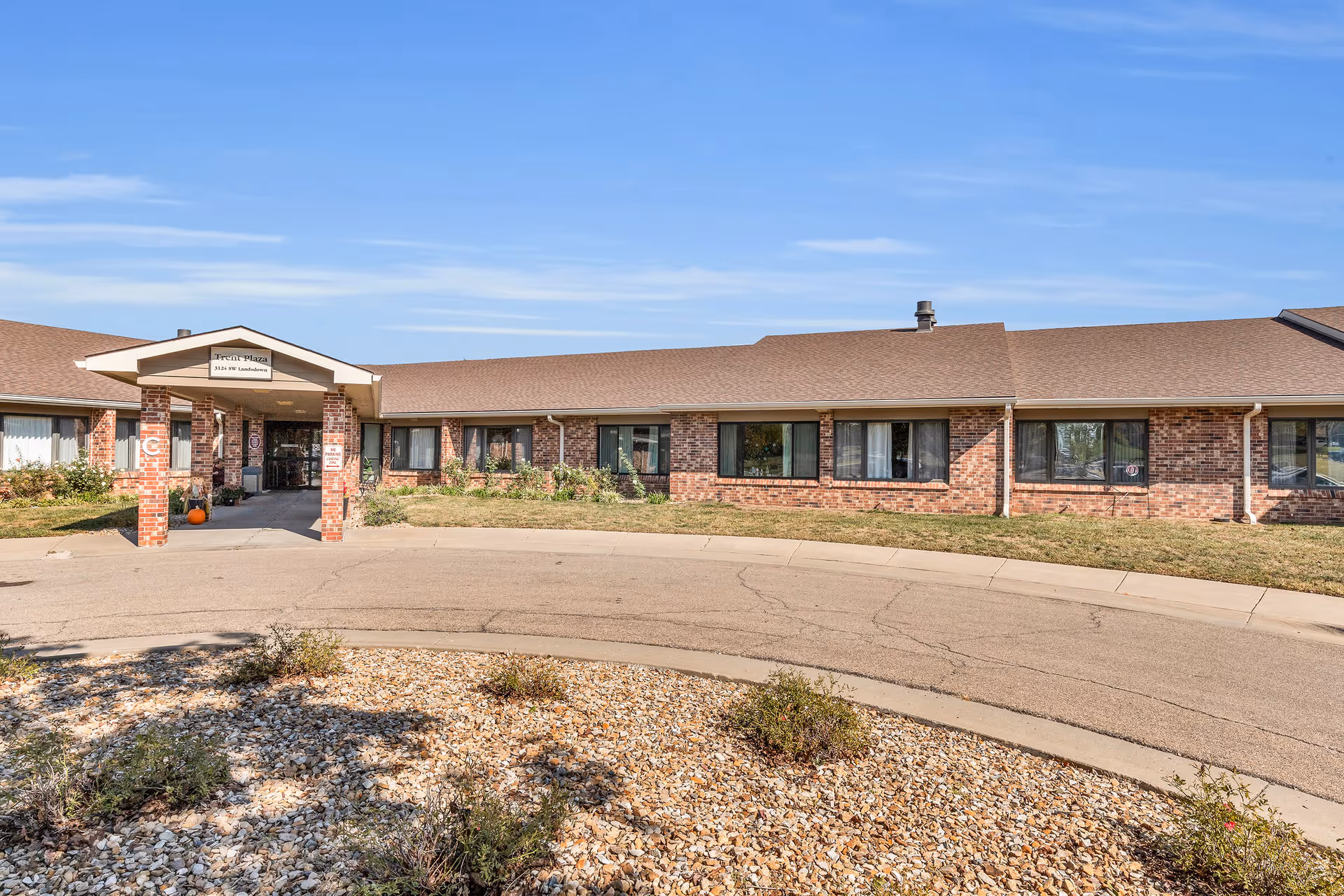 Front entrance of a single-story brick senior living facility with a covered portico and circular driveway.
