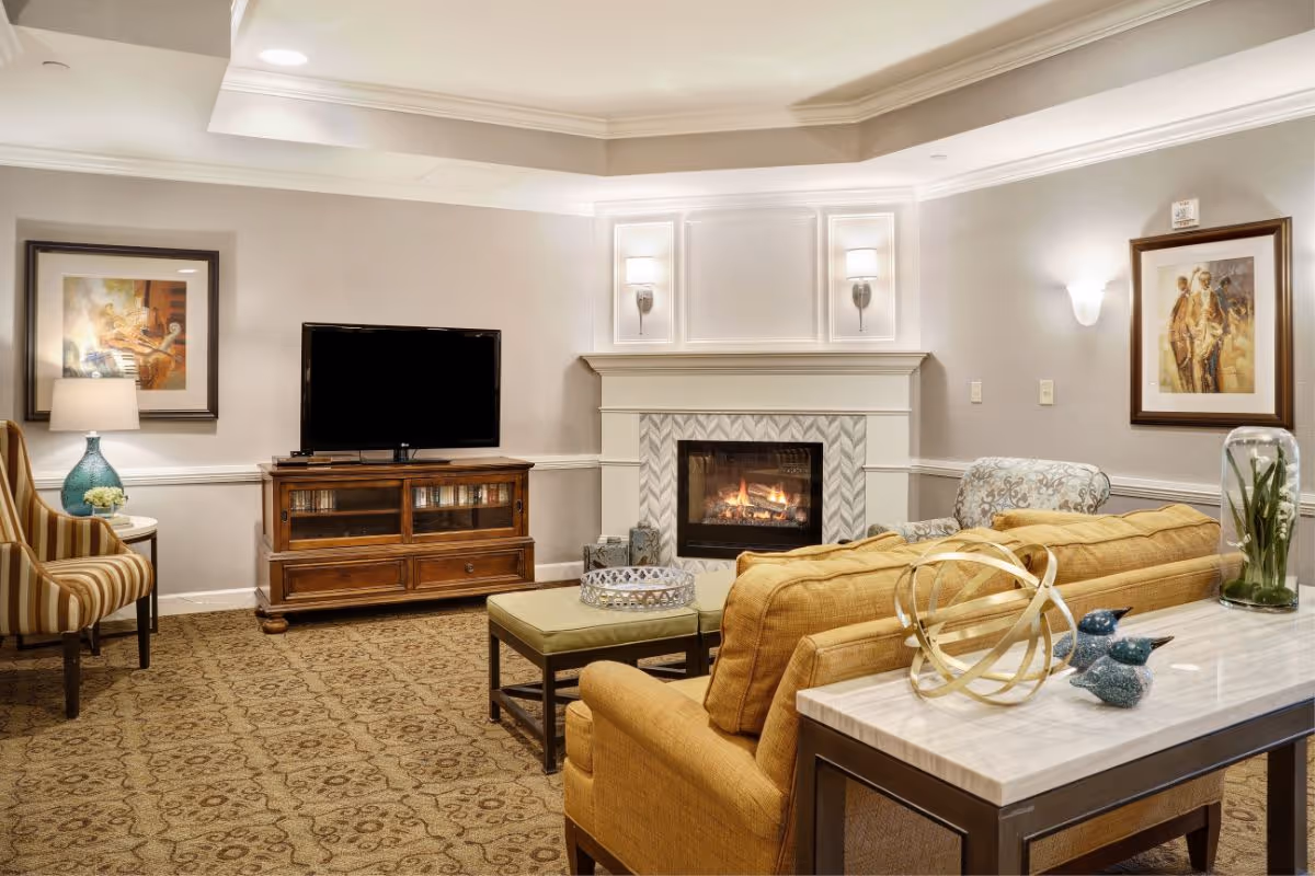 Cozy common living room with a fireplace, television, sofa and armchairs.