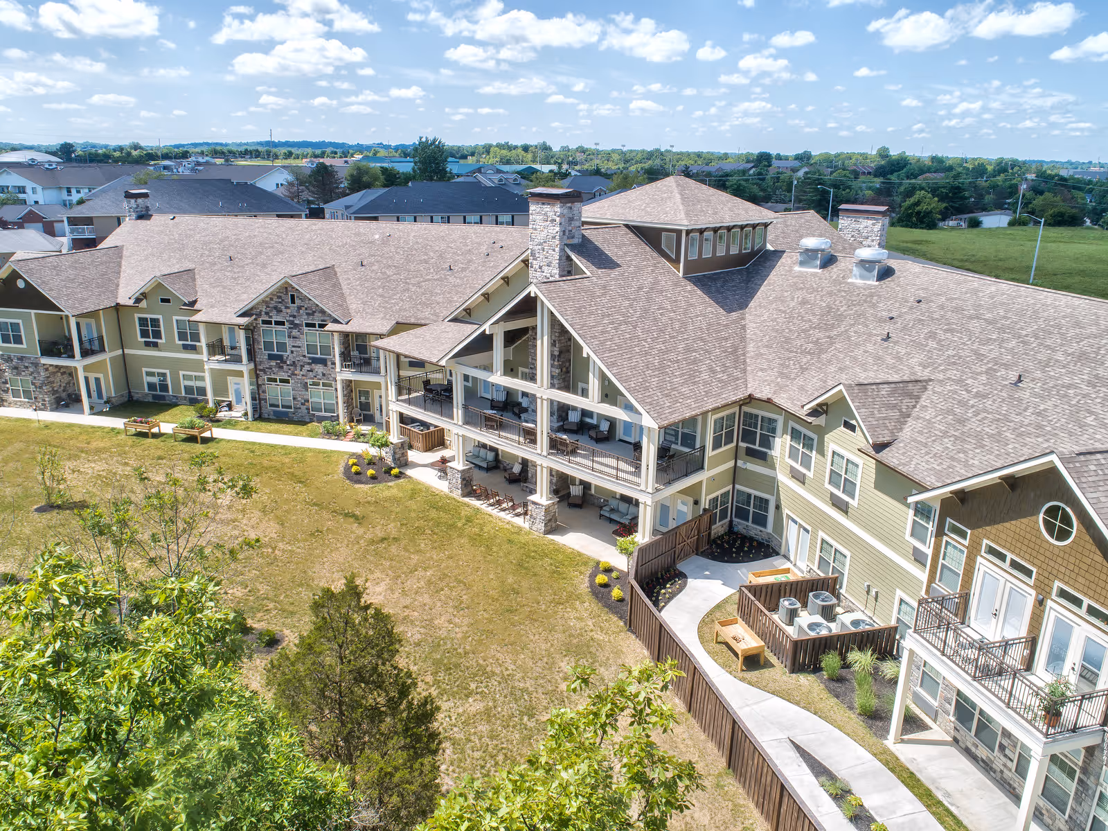 Aerial exterior view of a multi-story senior living building with balconies overlooking a grassy courtyard.