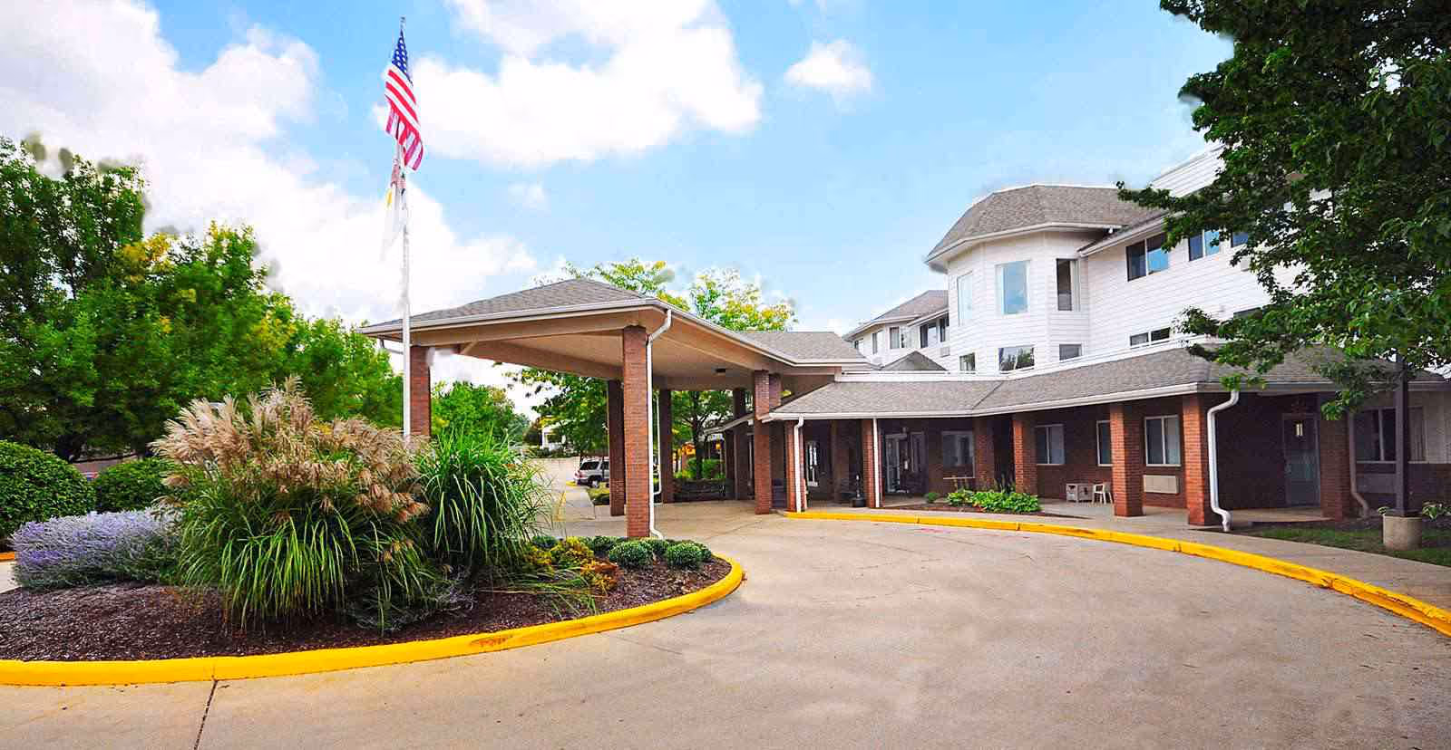 Exterior view of Solstice Senior Living at Joliet with a circular driveway and American flag.