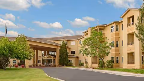 Exterior view of a beige multi-story retirement village with a covered entrance and landscaping.
