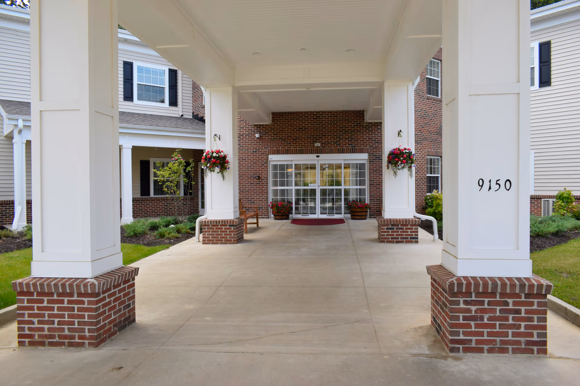 Covered entrance with white columns and brick bases at Danbury Mentor facility