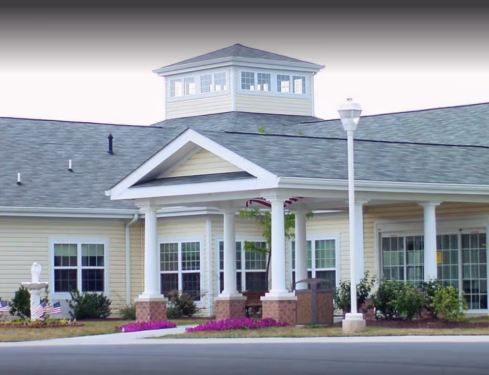 Exterior view of a beige senior living facility with a columned entrance porch.