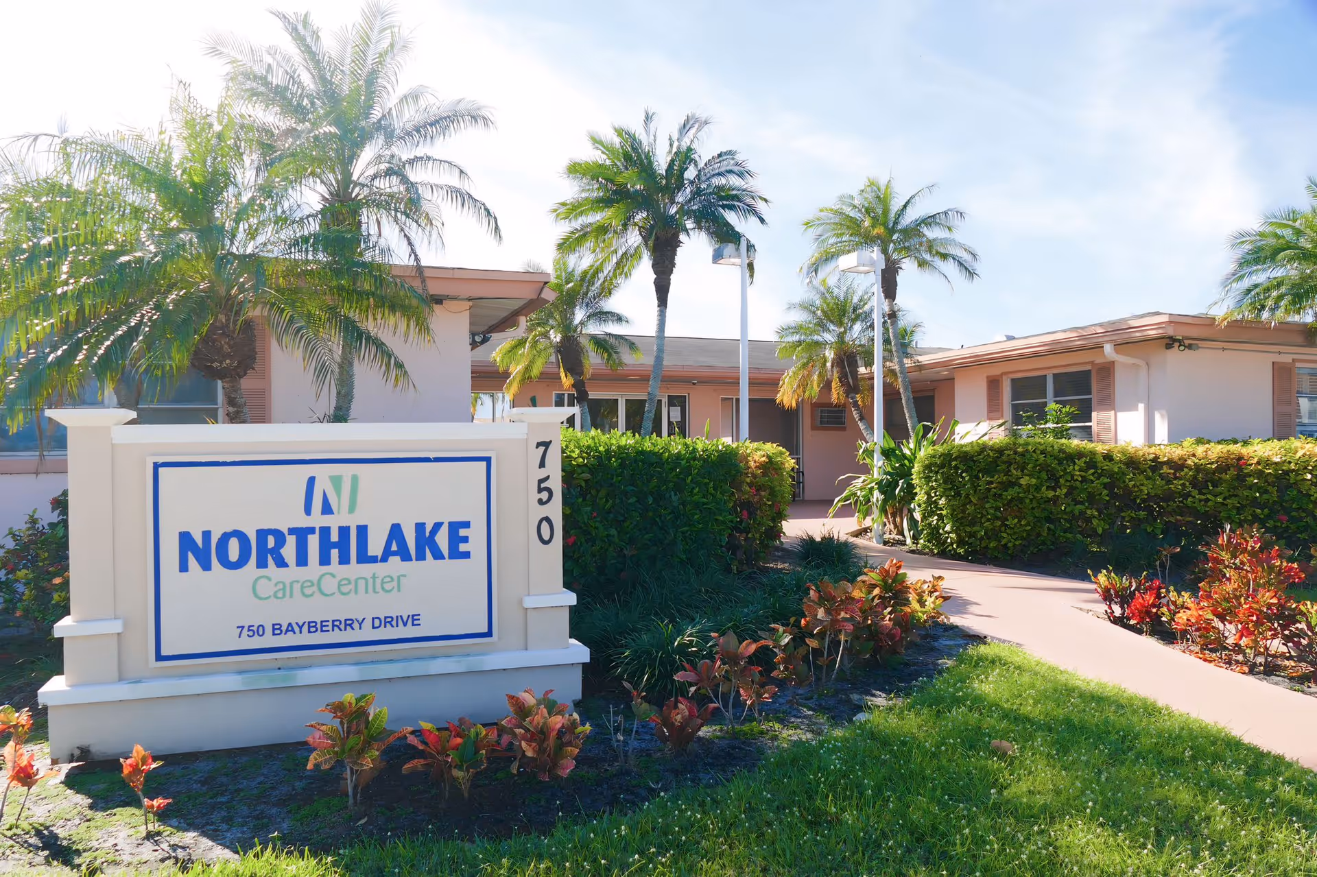 Front entrance of Northlake Care Center showing the facility sign, palm trees, landscaped walkway, and a single-story building.