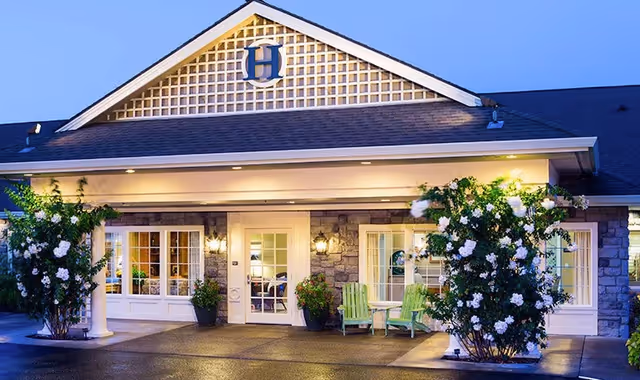 Front view of The Hampton and Ashley Inn Memory Care Community entrance with outdoor seating.