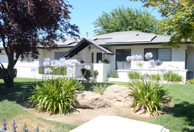 Exterior view of Chateau Jesadean with landscaped front yard and flowering plants.