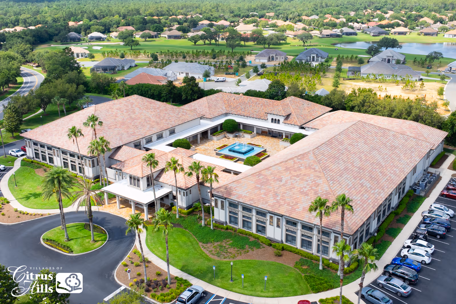 Aerial view of the Villages of Citrus Hills senior living complex with a central courtyard fountain, parking lot and landscaped grounds.