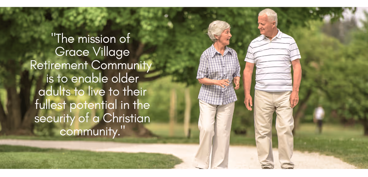 An elderly woman and man walking and talking on a gravel path in a green park-like setting with trees and grass.