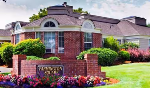 Brick senior living building with Farmington Square sign and well-kept landscaping.