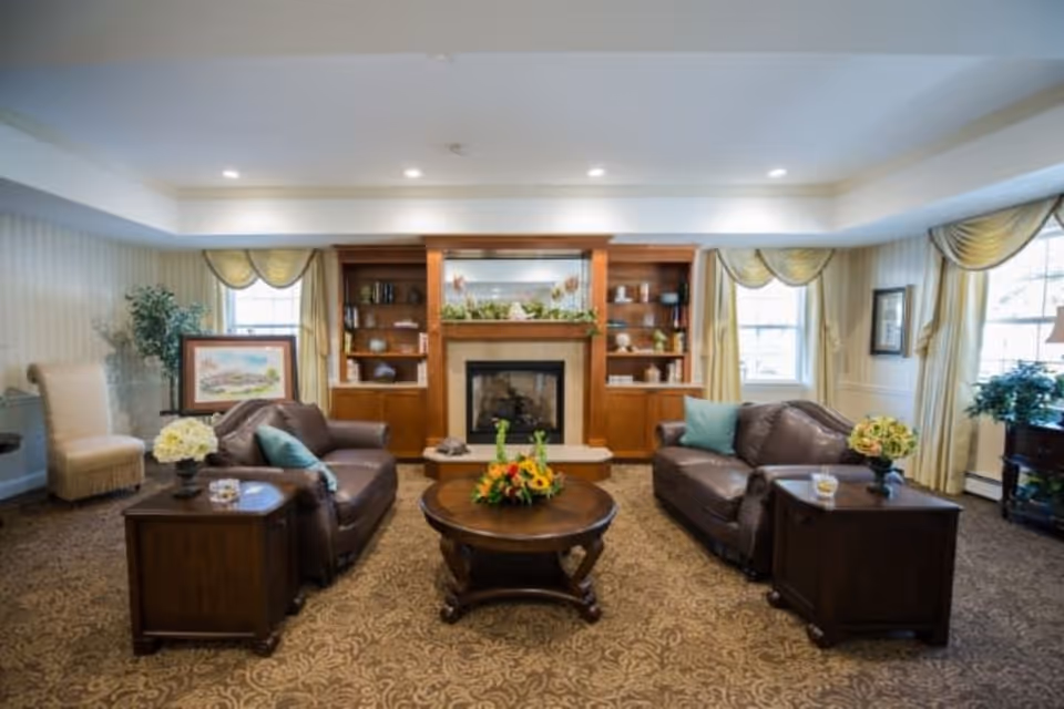 A cozy living room with two leather sofas facing a central coffee table and a fireplace flanked by built-in wooden shelves.