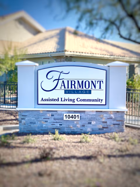 Sign reading 'Fairmont Village Assisted Living Community' with address number 10401 in front of a residential building.