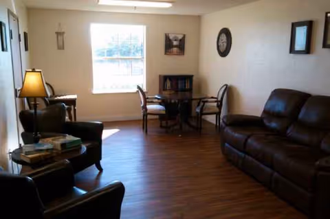 Cozy living room with brown leather sofas, chairs, a desk, and a window.