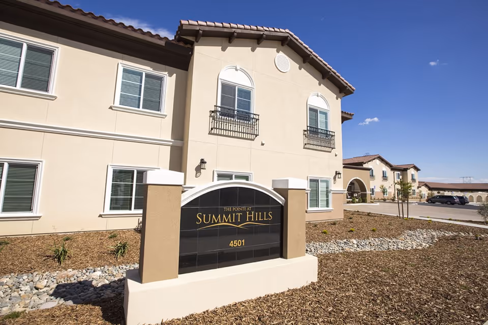 Front exterior of The Pointe at Summit Hills building with a landscaped entrance and a sign reading "SUMMIT HILLS" and "4501".