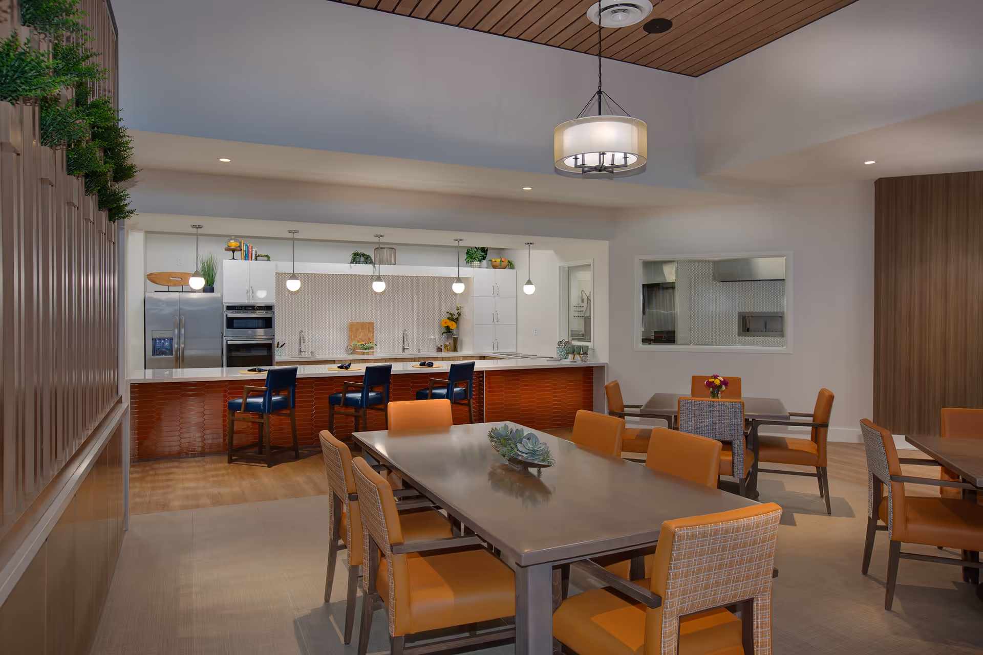 Modern communal dining area with tables and chairs facing an open kitchen and bar seating.