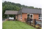 Brick single-story building with a covered entrance, lawn, black metal fence, and a sign for Mountain View Rehabilitation and Senior Living Center.