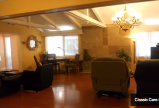 Spacious living room with multiple chairs and recliners, a dining table by the windows, a fireplace, and exposed ceiling beams.