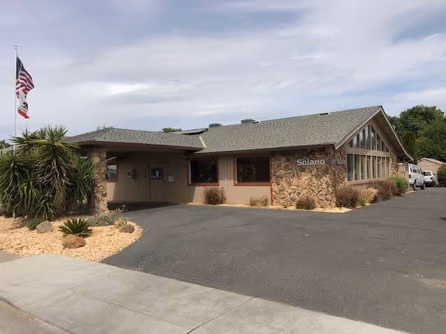 Exterior view of Solano Life House Assisted Living & Memory Care with flag and parking.