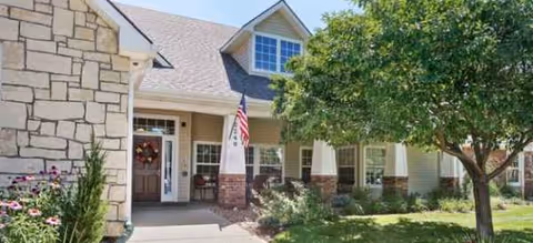 Front view of Brookdale Longmont senior living facility entrance with flag and trees