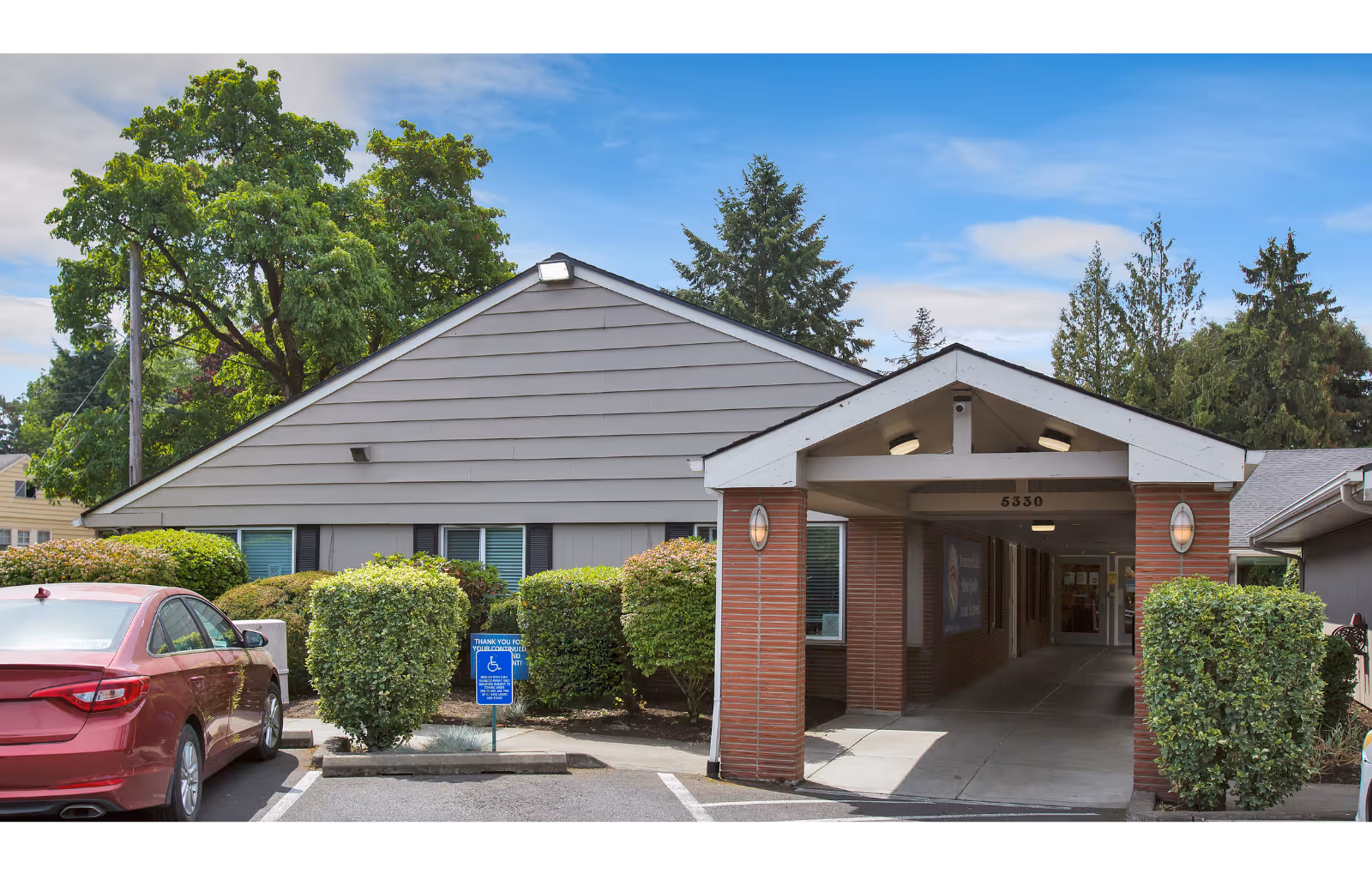Front exterior of the Porthaven Post Acute building showing a covered entrance drive, shrubbery, and a parked red car.