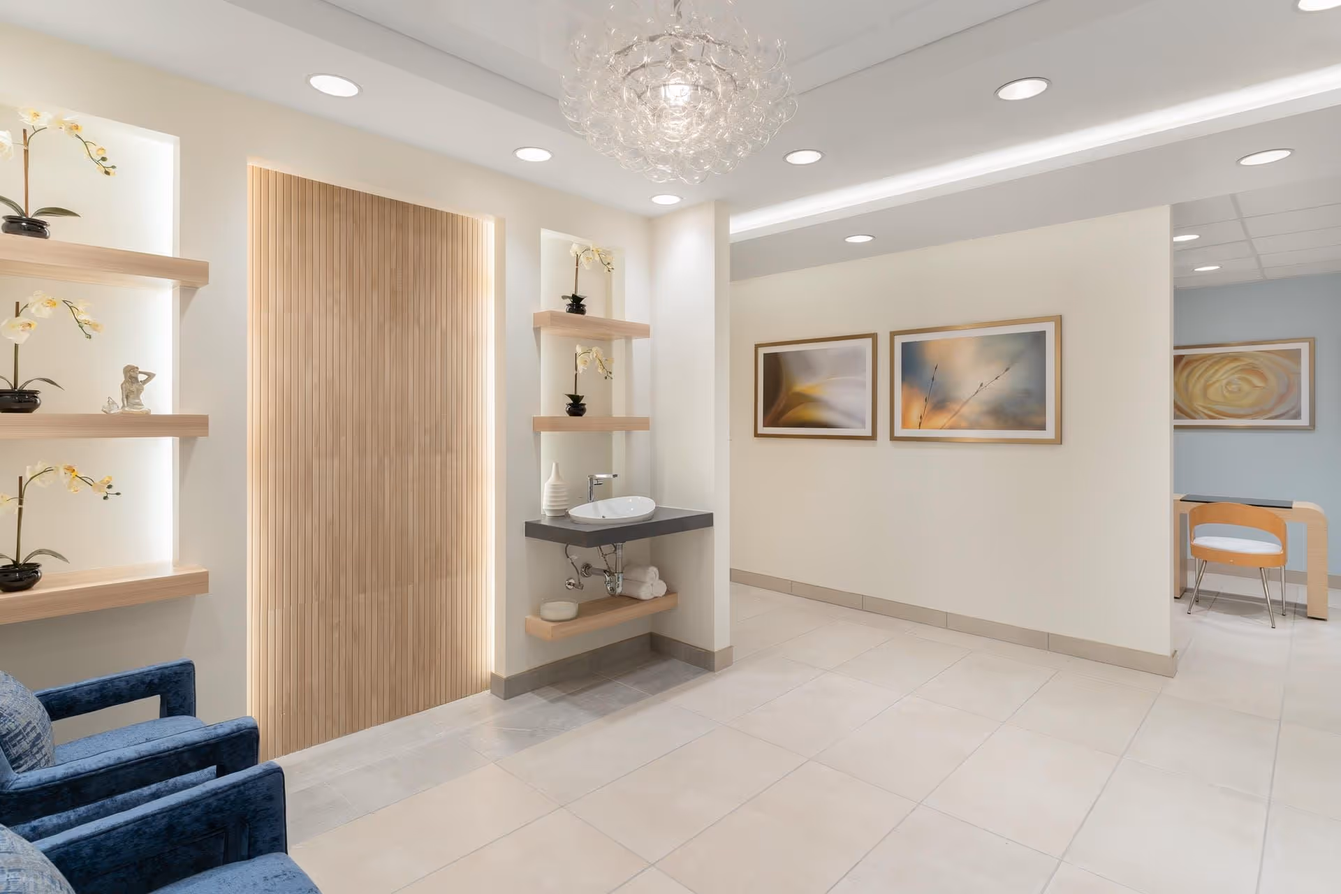 A modern reception area with decorative shelves, a sink, and artwork on the walls.