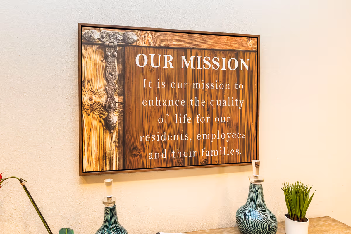Framed wooden 'Our Mission' sign on a wall above a table with decorative vases and a small potted plant.