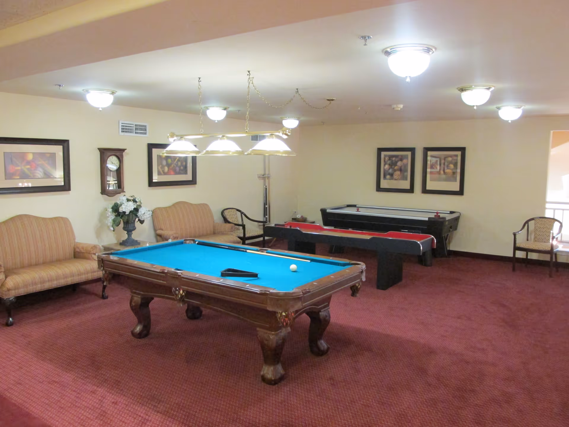 Recreation room with a pool table, an air hockey/table game, seating and framed artwork on the walls.