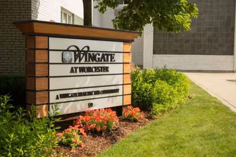Exterior sign for Wingate at Worcester, with landscaping and a sidewalk.