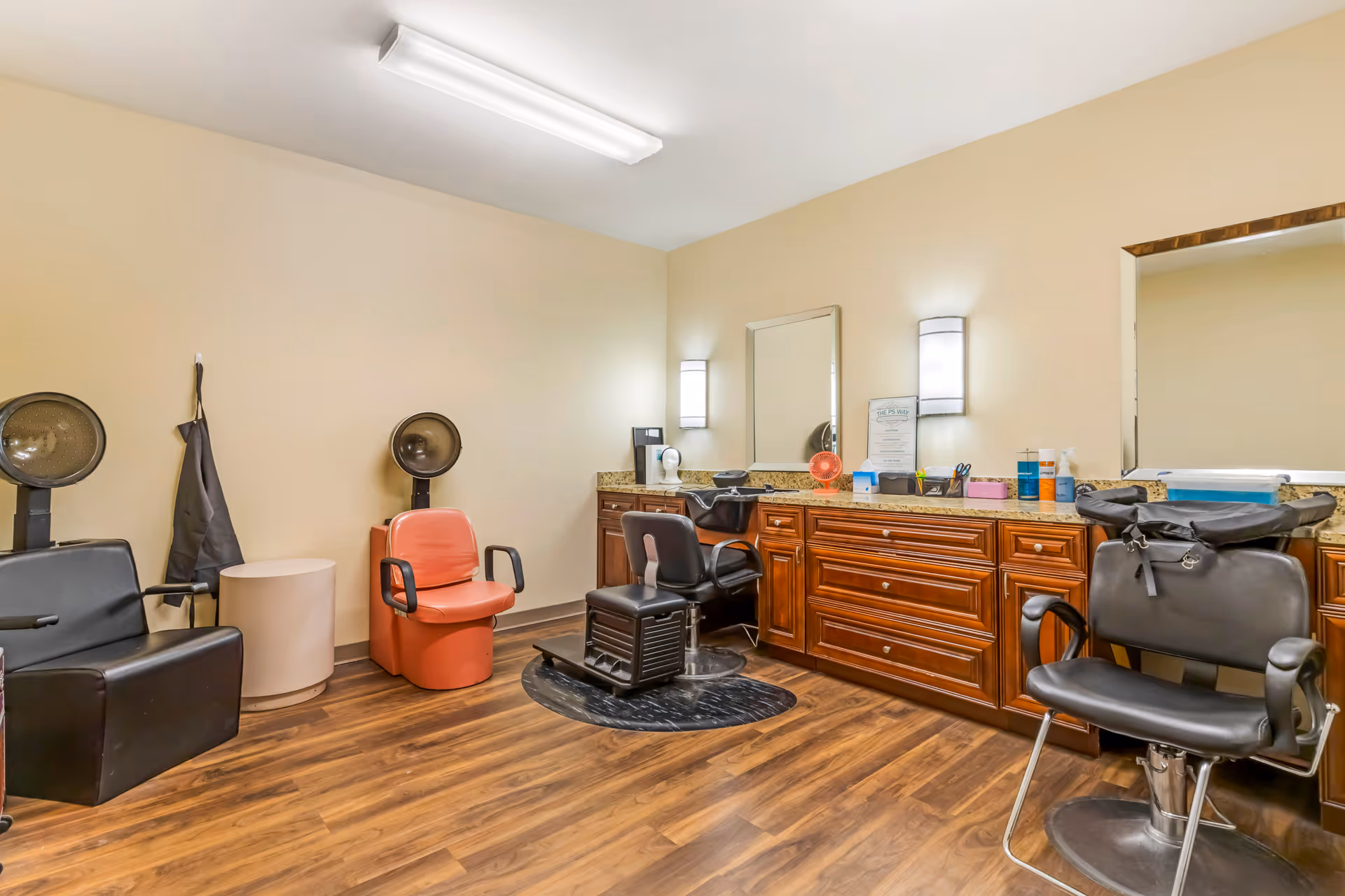 Salon area with styling chairs, mirrors, and wood cabinets in a senior living facility.