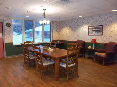 Cozy dining room with a wooden table, chairs, and seating along a wallpapered wall.