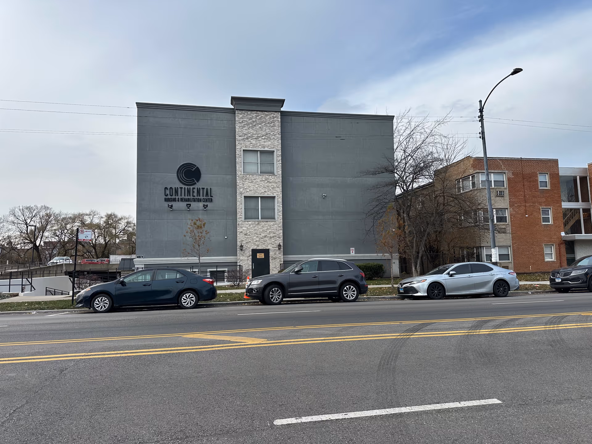 Front exterior of the Continental Nursing & Rehabilitation Center building with several cars parked along the street.